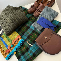 Collection of clothing and accessories including a sweater, shoes, and a bag on a white surface.
